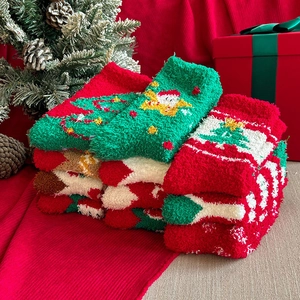 Detail of Christmas coral fleece socks with Santa and tree patterns in gift packaging