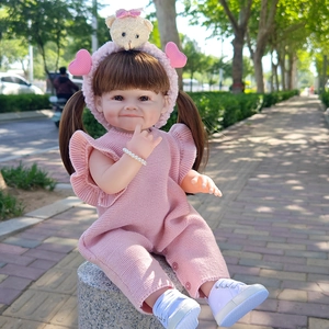 Detailed view of 55cm reborn doll wearing pink knit romper and cute bear headband