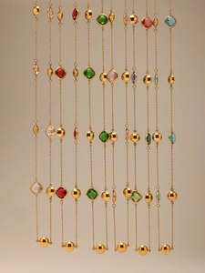 Présentation verticale de colliers doubles rangs avec pierres en verre coloré et dorure 18k