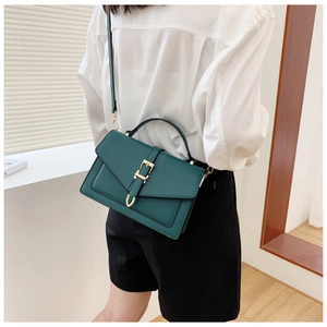 Detail of dark green PU leather handbag featuring a gold lock closure and top handle