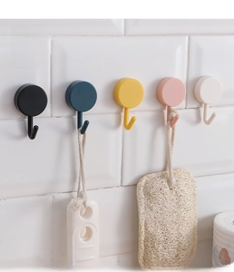 Close-up of five colorful round adhesive hooks installed on a white tiled wall