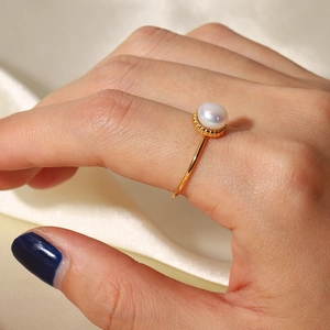 Elegant french style gold ring with freshwater pearl shown on model hand over silk