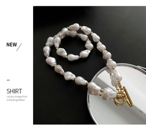 Close-up of baroque pearl necklace with gold metal spacers and toggle clasp on black background