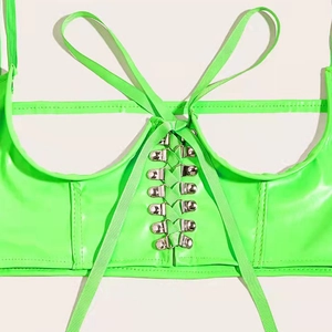 Détail d'un corset en cuir verni vert fluo avec œillets métalliques et lacets croisés