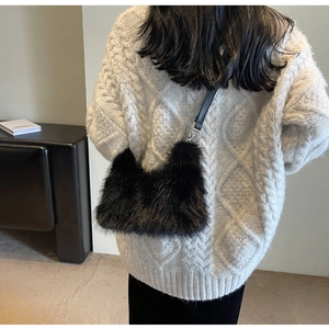 Detail of black faux fur handbag with leather strap paired with a chunky cable knit sweater