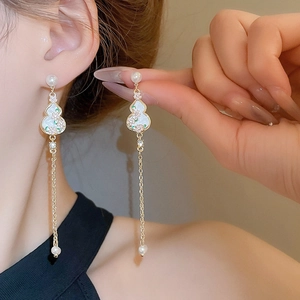 Detail of long tassel earrings with hand-painted gourd and elegant pearl accents