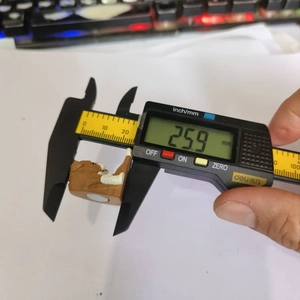 Digital caliper measuring the 25.9 mm width of a brown resin animal figurine magnet
