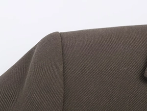 Macro shot of high-quality twill fabric and shoulder seam on dark olive suit jacket