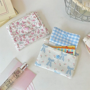 Trois porte-cartes en tissu assortis avec motifs floraux et à carreaux sur un bureau