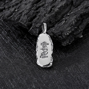 Vue macro d'un pendentif en acier inoxydable argenté avec mantra sanskrit gravé