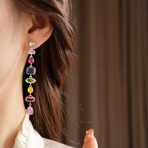 Close-up of colorful teardrop gemstone tassel earrings on model with silver plating