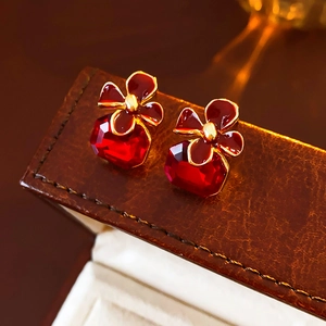 Close-up of vintage red gemstone flower earrings on a luxury brown leather box