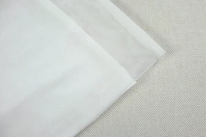 Close-up of white mesh fabric showing fine net texture and semi-transparent layers