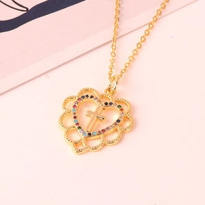 Collana con pendente a cuore dorato con croce e zirconi colorati su sfondo rosa