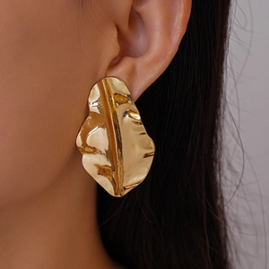 Close-up of gold irregular leaf earrings with metallic texture and crinkle finish