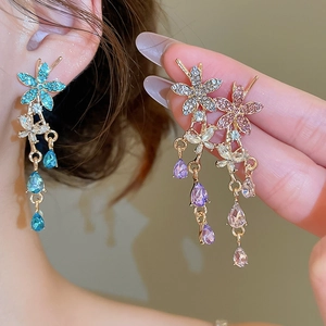 Detail of floral drop earrings with colorful crystals and long tassels on a model