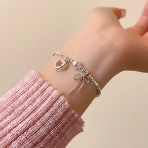 Detailansicht des Perlenarmbands mit silberner Schleife, rosa Herzzirkon und weißer Perle