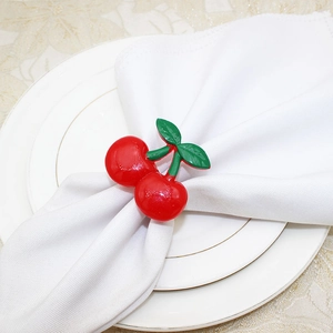 Macro shot of a red cherry napkin ring with green leaves on a white linen napkin