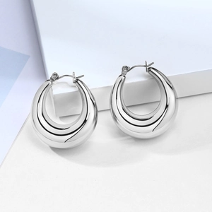 Macro shot of silver drop hollow earrings with reflective metallic finish on a white background