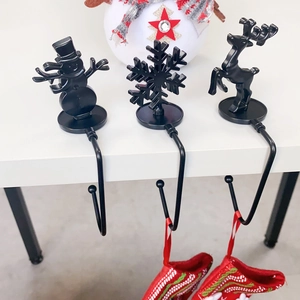 Close-up of black metal Christmas stocking hooks with snowman snowflake and reindeer designs