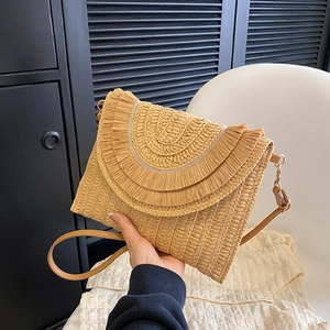 Detail of raffia woven crossbody bag with layered fringe and natural wooden tones