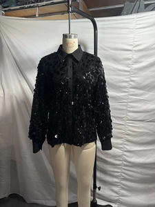 Detail of black long sleeve sequin shirt featuring a lapel collar and button-up front