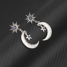 Detailed macro view of silver star and moon earrings featuring deep purple crystal inlay