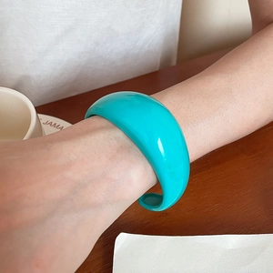 Close-up of a wide cyan blue resin open cuff bracelet with a glossy polished finish