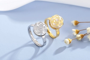 Detail of hollow camellia flower ring with white bead in gold and silver finish