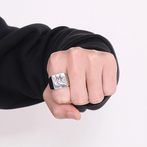 Men's stainless steel signet ring with unique cracked texture on a square flat surface