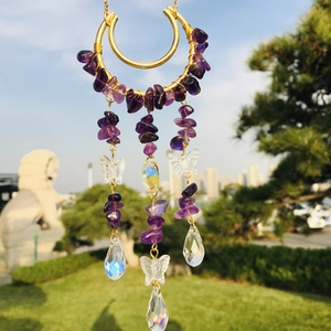 Detail of purple crystal suncatcher with golden moon frame and crystal butterfly charms