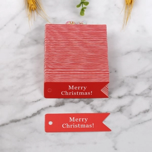 Etichette regalo rosse in carta a coda di pesce con scritta Merry Christmas su marmo