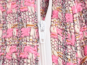Détail du tissu en tweed rose montrant la texture et la fermeture éclair blanche