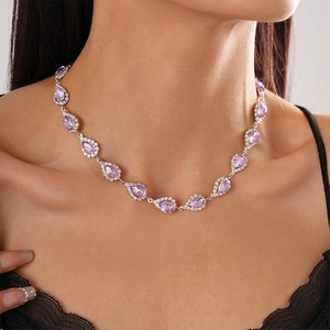 Close-up of luxury silver-toned necklace with purple pear-cut crystal pendant on woman neck