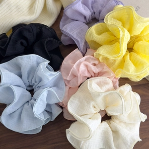 Flat lay of six colorful pleated oversized hair scrunchies on a dark wood background