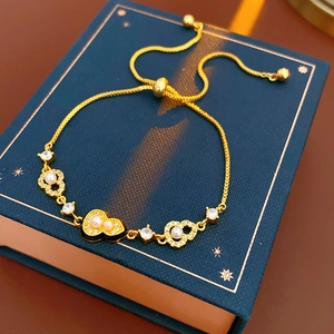 Detail of adjustable gold heart bracelet with pearls and crystals on blue jewelry box