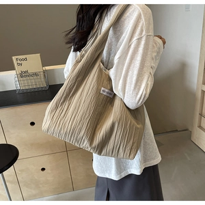 Detailansicht beige Plissee-Einkaufstasche mit KISS YOURSELF-Label und weicher Textur