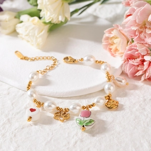 Luxurious pearl bracelet with ceramic heart and tulip charms on a white pedestal