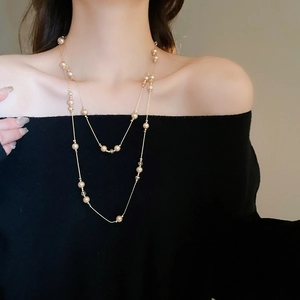 Collier double épaisseur en perles champagne et chaîne dorée porté sur un modèle en noir