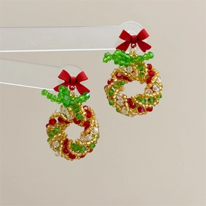 Detailed view of handmade beaded Christmas wreath earrings with a vibrant red bow