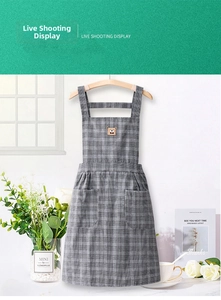 Detail of grey checkered cotton apron featuring a cute brown bear patch and side pockets