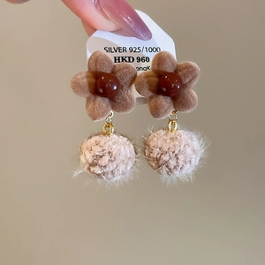 Detail of vintage flower earrings featuring brown flocking and soft pink fur pom-poms