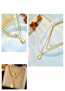 Detailed view of triple-layered gold chain necklace with heart and lock pendants