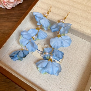Détail de boucles d'oreilles à fleurs bleues en tissu avec perles et crochets dorés