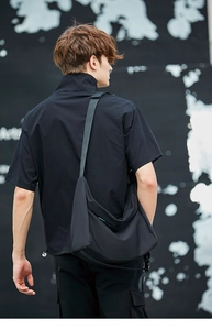 Borsa a tracolla nera in nylon vista da un'angolazione laterale posteriore su un modello