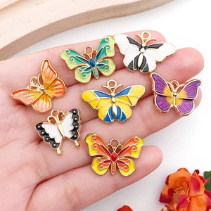 Set of seven colorful enamel butterfly pendants in a palm for DIY jewelry making accessories