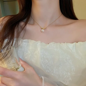 Elegant gold-plated fishtail necklace with white pearl pendant worn on model neck