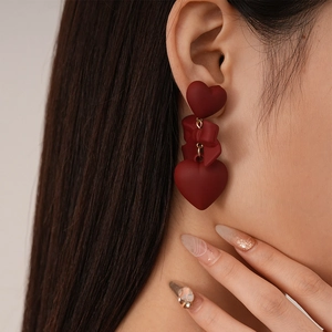 Vintage Ankara red bow and heart drop earrings with silver needle on female model