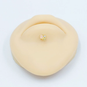 Gros plan de la boucle d'oreille en acier doré avec gemme rose et papillon sur oreille