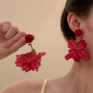 Detail of red flower tassel earrings with green beads worn for a bridal fashion look
